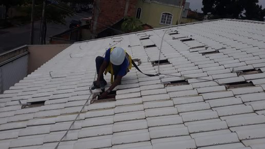 Instalador fixando estrutura de módulos fotovoltaicos em telhado cerâmico